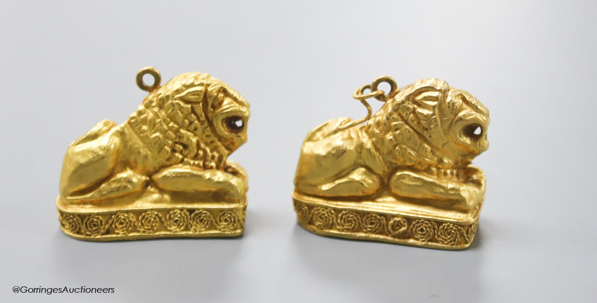 A pair of Etruscan style yellow metal recumbent lion pendant charms, 25mm, gross 11.1 grams (tests as 22ct)